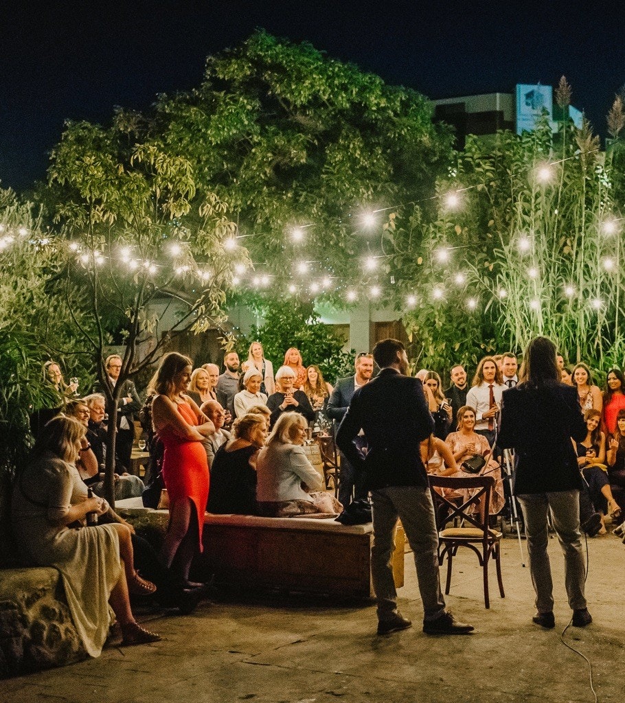 Wedding reception speeches outside under fairy lights.